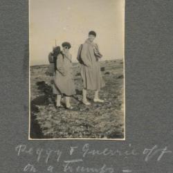 Black and white photograph of two women in trenchcoats standing in an open field