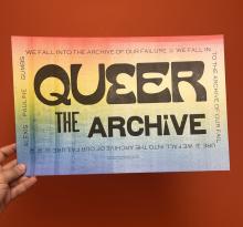 Hand holding Queer the Archive poster
